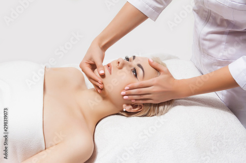 Face massage. Close-up of a young woman receiving spa massage in a beauty and spa salon by beautician. Spa skin and body care. Beauty face care. Cosmetology.