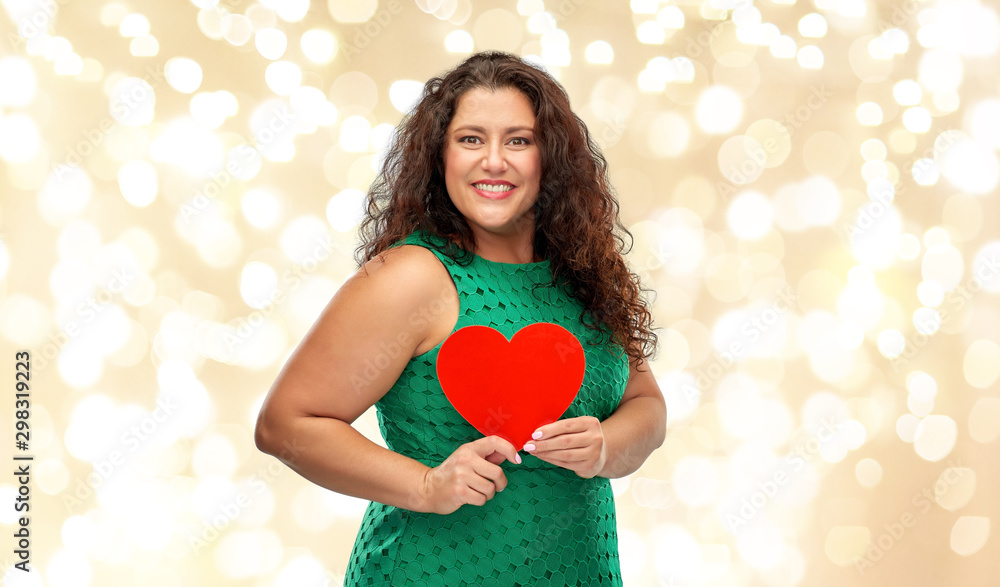 valentine's day, holidays and love concept - happy woman in green dress holding red heart over festive lights on beige background valentine's day, holidays and love concept - happy woman in green dress holding red heart over festive lights on beige background
