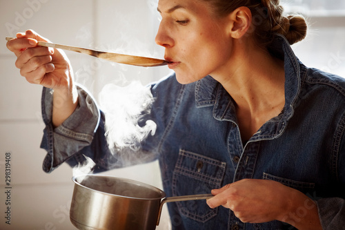 Φωτογραφία Woman tasting food while cooking in kitchen