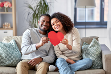 love, valentines day and relationships concept - happy african american couple holding red heart together at home