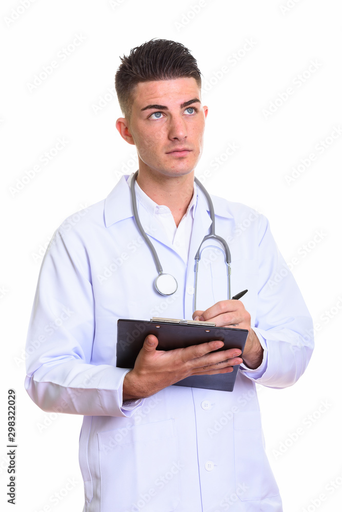 Young handsome man doctor writing on clipboard while thinking Young handsome man doctor writing on clipboard while thinking