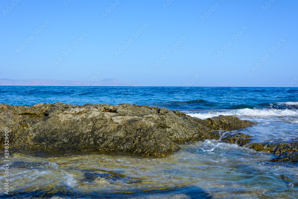 part of the rocky coast and calm sea. silhouette of mountains on the horizon