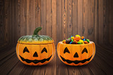 Halloween Jack o Lantern pail overflowing with colorful chocolate on wooden background