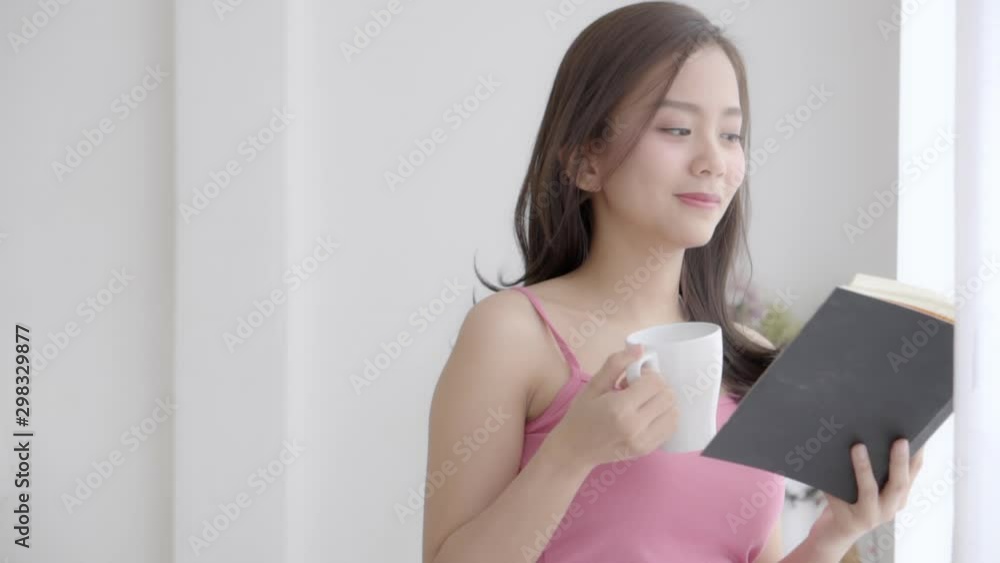 Beautiful young asian woman relax and leisure standing learning with reading book and drink coffee for exam at home, girl is student knowledge with study education and lifestyle concept, slow motion. Beautiful young asian woman relax and leisure standing learning with reading book and drink coffee for exam at home, girl is student knowledge with study education and lifestyle concept, slow motion.