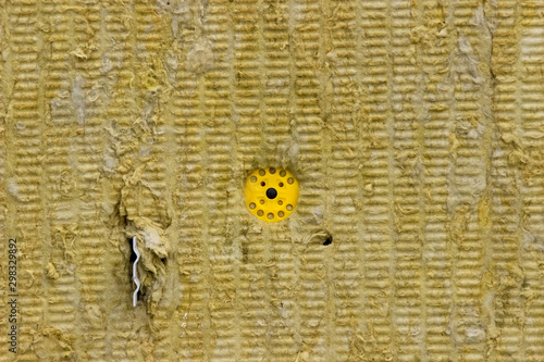 Closeup of mineral fiber board installed as thermal insulation attached to a wall with mechanical fastener