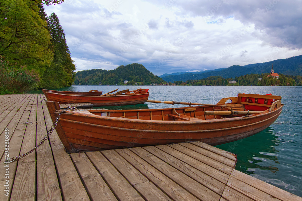 utiful autumn landscape with three wooden boats moored on Bled Lake (Blejsko jezero). Famous touristic place and travel destination in Europe. Bled, Slovenia