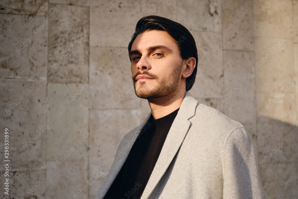 Portrait of confident brunette man in coat intently looking in camera outdoor Portrait of confident brunette man in coat intently looking in camera outdoor