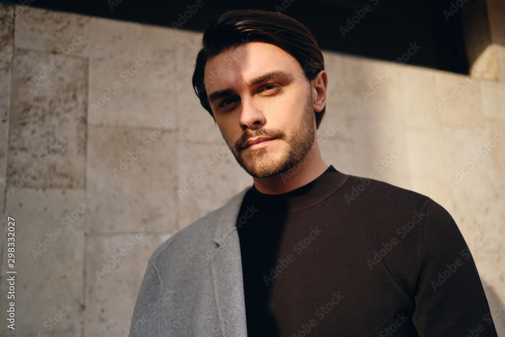 Portrait of young attractive man with coat on shoulder confidently looking in camera outdoor Portrait of young attractive man with coat on shoulder confidently looking in camera outdoor