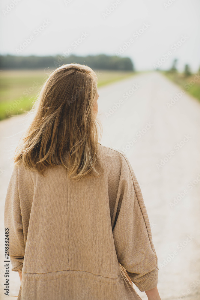 Woman in dress is walking on the road. Summertime. Woman in dress is walking on the road. Summertime.