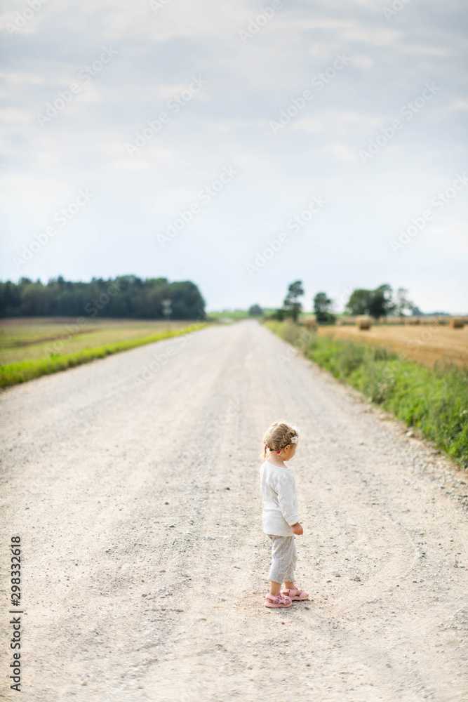 Obraz premium Little girl on the road in countryside. Summer.