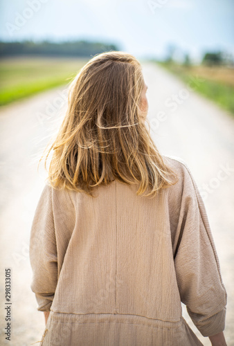 Woman in dress is walking on the road. Summertime.