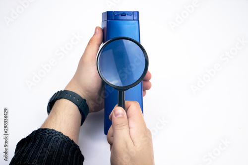 Chemical components on the shampoo label. A hand holds a blue jar and a magnifier, where the harmful ingredients of a detergent are written in close up. Place for an inscription. photo