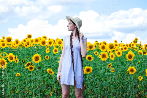 Young beautiful woman in a straw hat in a field of sunflowers