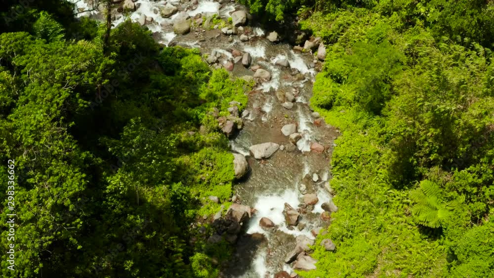 Mountain river with large stones in the rainforest, aerial view. River in the green forest. River flowing through boulders, Camiguin, Philippines. Mountain river with large stones in the rainforest, aerial view. River in the green forest. River flowing through boulders, Camiguin, Philippines.