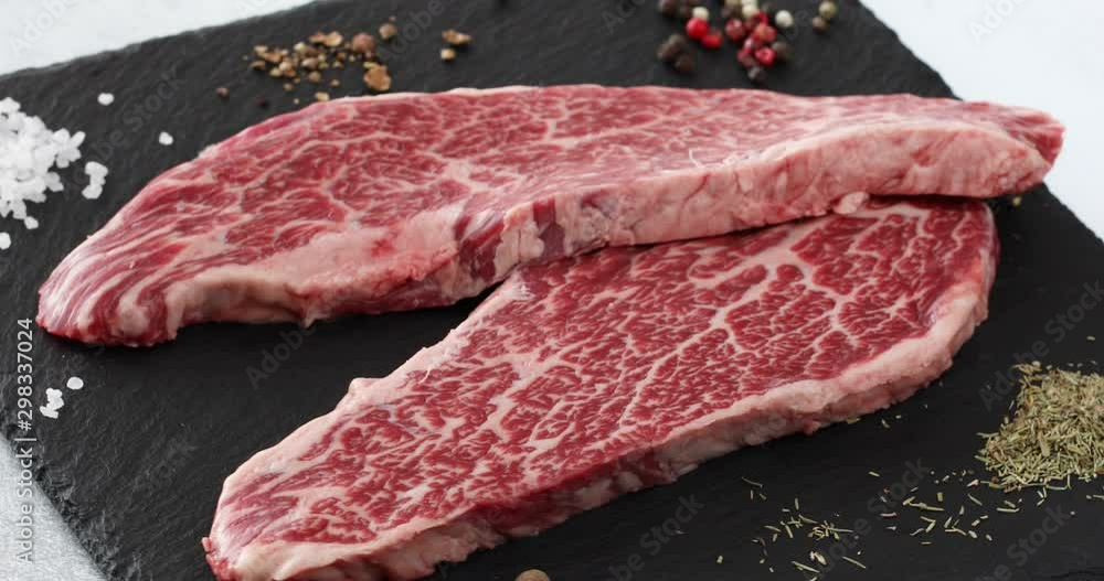 Vidéo Stock Fresh raw beef meat Denver Steak with peppercorns, seasonings and spices, ready to