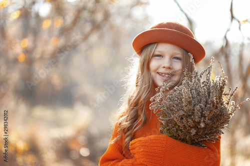 Little cute girl in the autumn forest with a bouquet of leaves in her hands. Autumn mood. Thanksgiving Holiday Concept.
