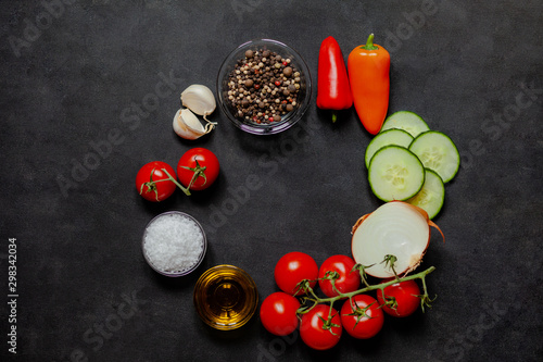 Ingredients for traditional spanish homemade cold summer soup gazpacho: tomato, cucumber, pepper, olive oil, garlik, onion, salt. Fresh and healthy lunch. Black background, flatlay, top view