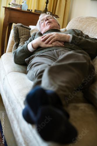 Senior man having midday sleep on sofa photo