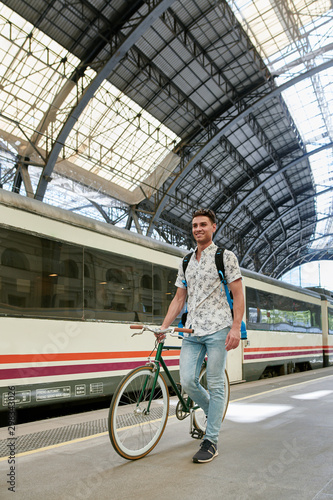 Man pushing bicycle through a station
