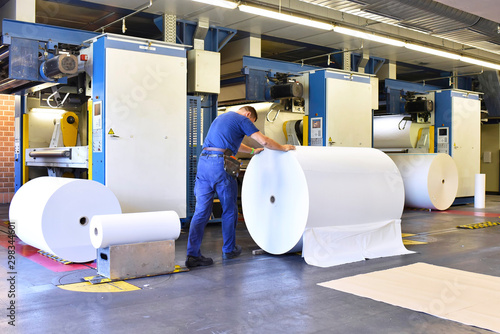 Man moving paper roll in a printing shop