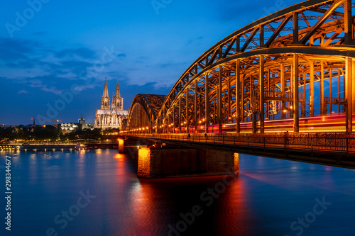 Cologne cathedral and Hohenzollern Bridge over Rhine river at dusk