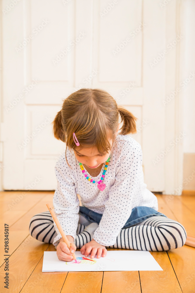 Little girl sitting on wooden floor painting with crayon Little girl sitting on wooden floor painting with crayon
