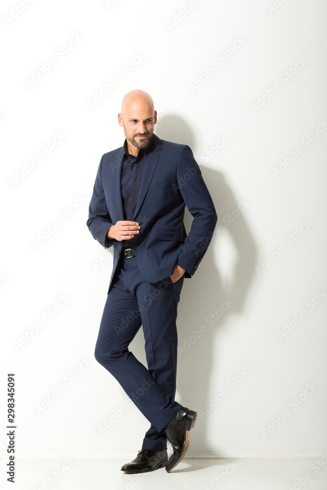 Bald man with beard wearing blue suit standing in front of white background Stock Photo Adobe
