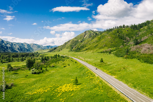 Aerial view of road Chuysky Trakt in green mountain valley on sunny summer day. Nature landscape on Federal Highway R256 near Shebalino, Altai Republic, Siberia, Russia