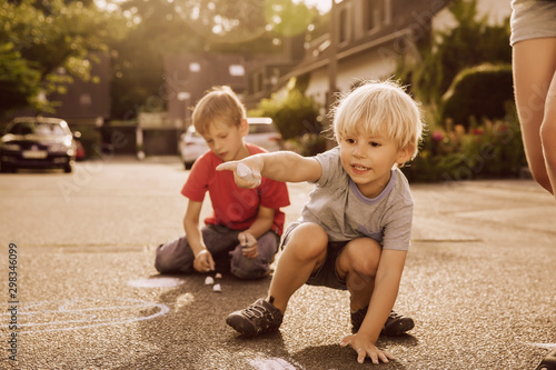 Children using sidewalk chalk in their neighborhood photo