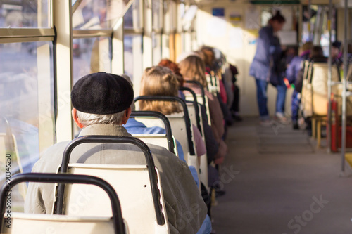people ride a tram with large windows on a sunny autumn day. public transport and passengers.