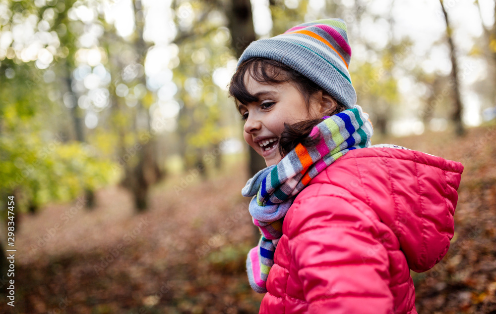 Happy little girl in the woods wearing cap and scarf in autumn Happy little girl in the woods wearing cap and scarf in autumn