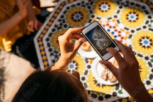 Close-up of woman taking a picture of cakes in a Moroccan cafe photo