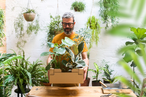 Man holding cardboard box with new plants for his terrace