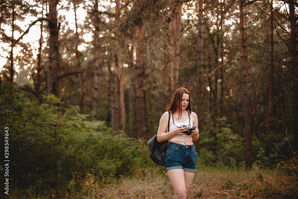 Young woman holding camera while walking in forest Young woman holding camera while walking in forest