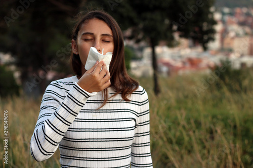 Young woman sneezing in the woods