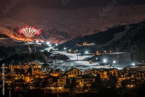 Night ski event with fireworks in Austrian village on snow white ski slope photo