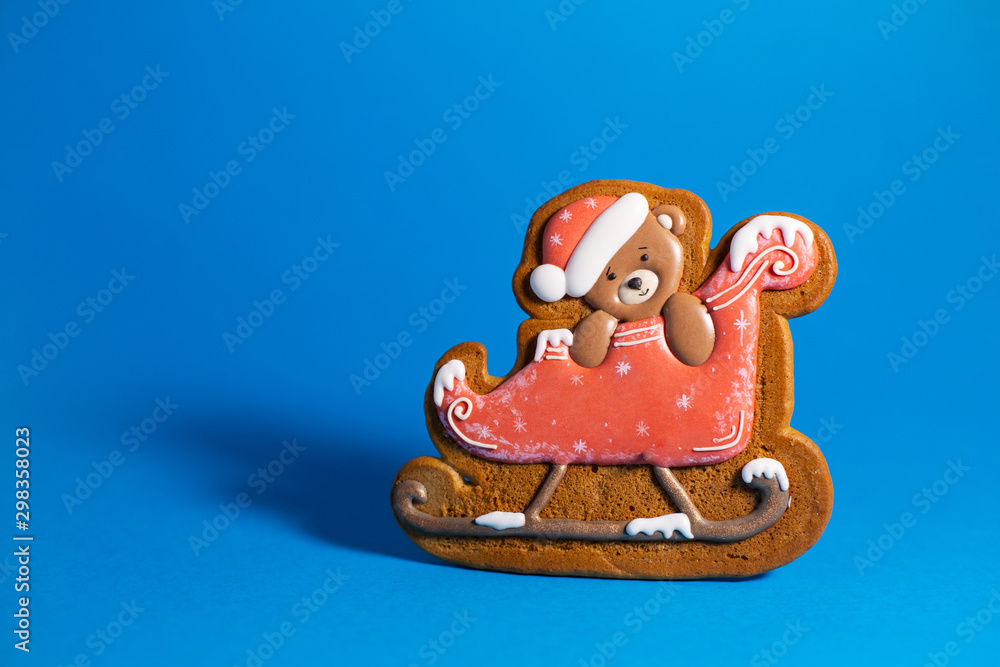 gingerbread cookie of little cute teddy bear on sleigh on blue background. Traditional Christmas food. Christmas and New Year holiday concept. Copyspace gingerbread cookie of little cute teddy bear on sleigh on blue background. Traditional Christmas food. Christmas and New Year holiday concept. Copyspace