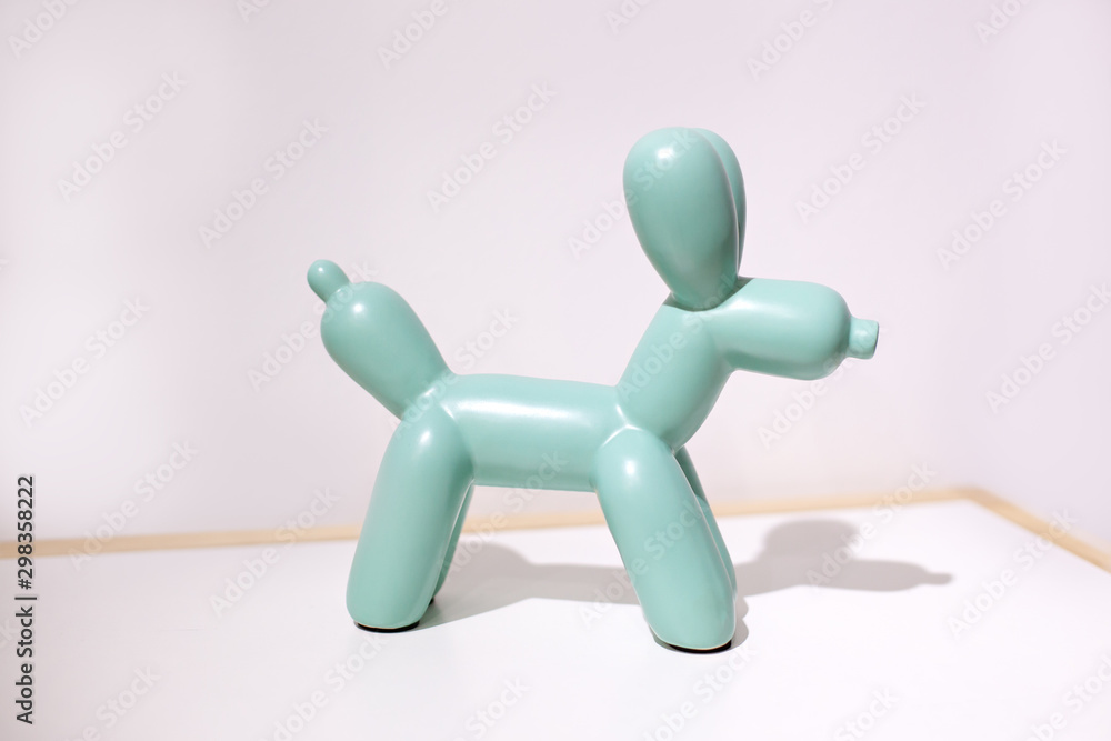 Ceramic dog doll on a white background. statuette of a dog in mint color stands on a table against a white wall in the interior of the house.. Ceramic figurine, dog breed isolated on white. Home decor Ceramic dog doll on a white background. statuette of a dog in mint color stands on a table against a white wall in the interior of the house.. Ceramic figurine, dog breed isolated on white. Home decor
