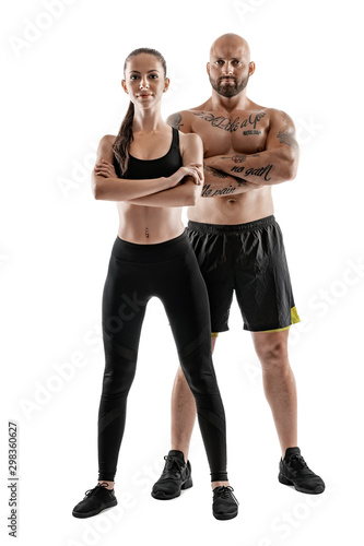 Athletic man in black shorts and sneakers with brunette woman in leggings and top posing isolated on white background. Fitness couple, gym concept.
