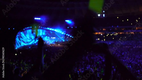 Big music concert at the stadium, people waving glow sticks