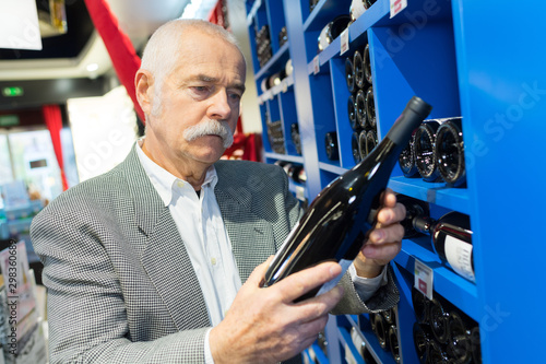 man in a supermarket chossing wine bottles photo