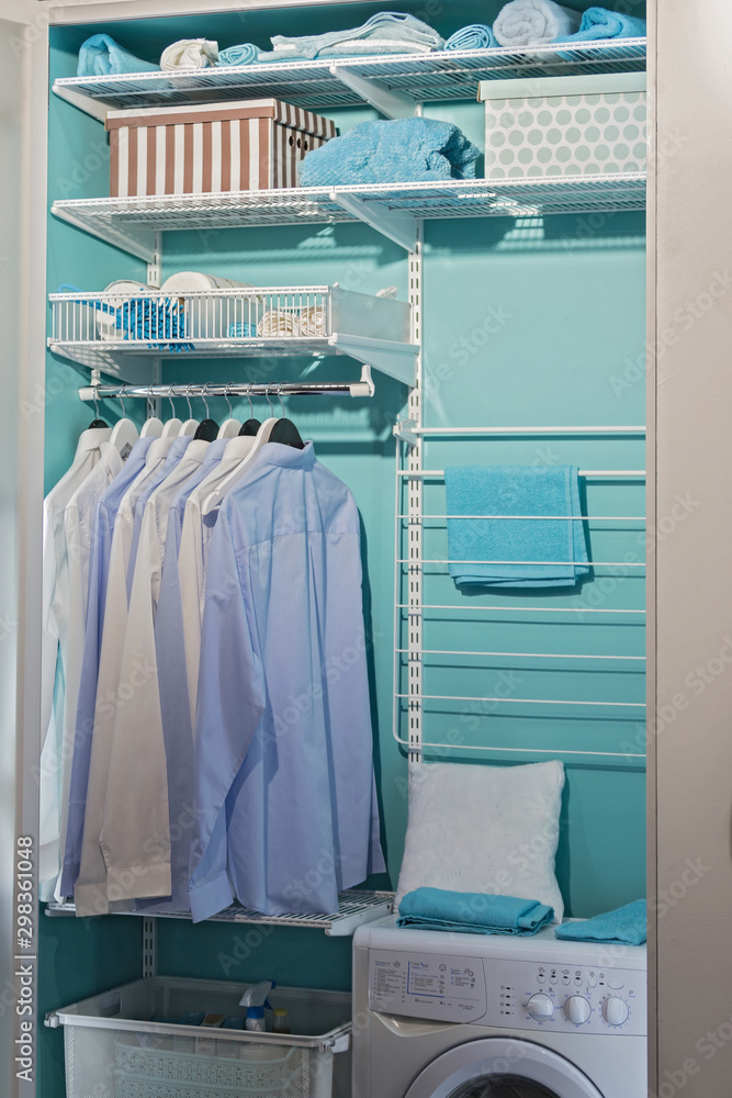 piles of clean clothes in laundry room. Laundry closet. Washing room, modern design with a laundry machine with hangers for clothes, an iron, shelves and a washing machine piles of clean clothes in laundry room. Laundry closet. Washing room, modern design with a laundry machine with hangers for clothes, an iron, shelves and a washing machine