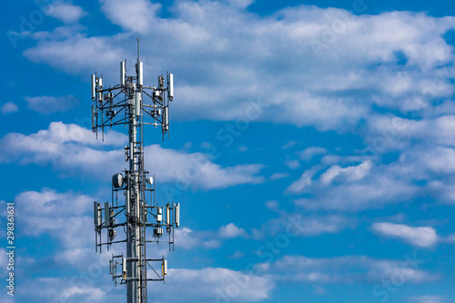 A low and wide angle view of a typical cell network antenna tower. Used to send and receive mobile network communications, with copy-space and cloudy blue sky. photo