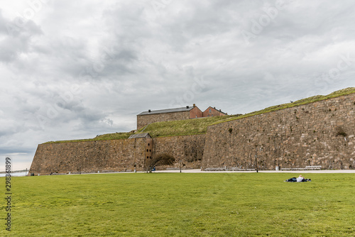 The fortress of Varberg and a boy and a girl are resting on the grass in front of the walls photo