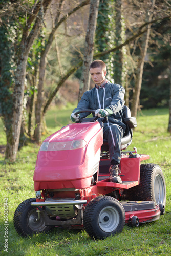 gardener driving a riding lawn mower in garden