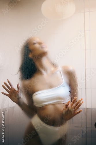 View of woman posing through shower glass
