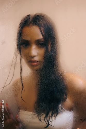 Direct view of young woman in white bikini looking through glass