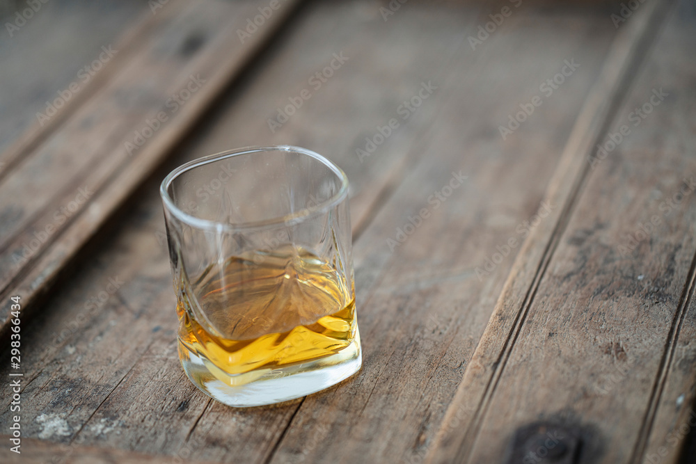 Detail of beautiful whisky glass with golden shimmering whisky on a rustic wooden used barrel Detail of beautiful whisky glass with golden shimmering whisky on a rustic wooden used barrel