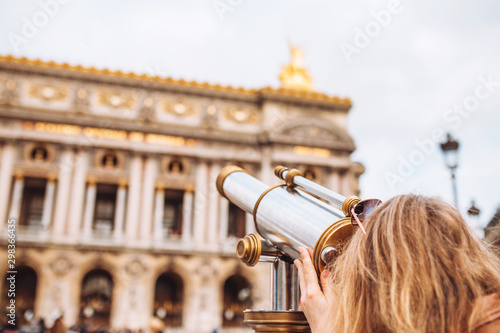 blonde girl examines a building through a telescope - tourist attractions