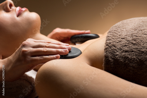 wellness, beauty and relaxation concept - close up of young woman having hot stone massage at spa photo